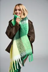 Bufanda tejida con flecos y textura suave, con diseño a cuadros en tonos verdes, amarillos y blancos.