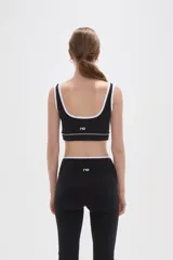 Top deportivo negro con detalles de ribete blanco en el escote y breteles. Presenta un diseño de corte cuadrado y ajuste al cuerpo.