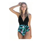 Malla enteriza bicolor de diseño combinado, con parte superior lisa en color negro de escote en V pronunciado con bordes ondulados, y parte inferior con estampado botánico de hojas verdes y flores rosadas sobre fondo negro. Cuenta con tirantes finos regulables.