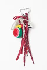 Llavero decorativo con mosquetón metálico en forma de corazón, que incluye una variedad de elementos colgantes: una pieza tejida a crochet con forma de sandía, una tira de perlas, cintas de raso rojas y cordones deportivos con punteras metálicas.