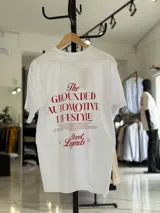 Remera oversize blanca de manga corta, con gran estampado tipográfico en color rojo en la espalda con la leyenda "The Grounded Automotive Lifestyle".