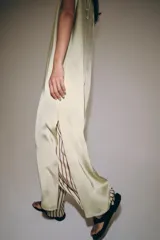 Vestido midi de Zara Woman Collection confeccionado en hilatura de viscosa con tejido satinado, de color beige. Presenta cuello subido, diseño sin mangas (manga sisa), bajo recto con aberturas laterales y cierre en la espalda con alamares.
