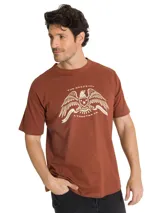 Remera de algodón color marrón con cuello redondo y manga corta. Presenta un estampado gráfico en el pecho con un águila y la inscripción The Original A Tractor Co.
