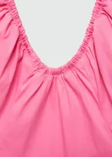 Vestido corto de color rosado con diseño evasé, escote halter con cuello fruncido y tirantes finos. Presenta un cuerpo con detalle fruncido elástico y cierre lateral de cremallera.