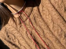 Gargantilla de strass plateado con tiento rojo.