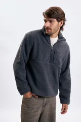 Buzo de sherpa en color gris oscuro, con cuello alto y cierre frontal parcial. Presenta un bolsillo frontal con cierre y diseño de manga larga.