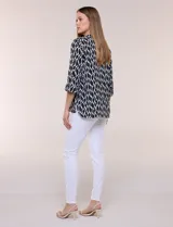 Blusa de calce suelto y caída ligera en color negro con estampado geométrico blanco. Presenta escote en V, cuello mao, abotonadura frontal metálica y bolsillos superiores en el pecho. Cuenta con mangas largas regulables con presilla y botón, ruedo redondeado con tajos laterales y canesú en la espalda.
