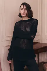 Sweater de punto calado color negro, con escote redondo y mangas largas. Presenta un diseño de tejido abierto y holgado.