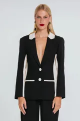 Blazer estructurado de color negro con solapas, ribetes de bolsillos, botones y paneles laterales en color marfil. Presenta cierre frontal de dos botones y bolsillos con solapa.