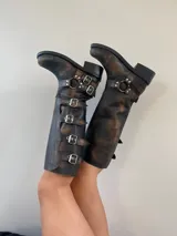 Botas de cuero negro de caña alta con múltiples correas con hebillas plateadas y suela de goma.