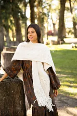 Ruana de lana merino color crudo, con diseño tejido de textura en relieve y terminación con flecos largos en el ruedo.