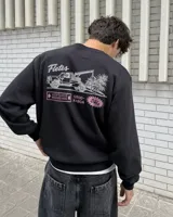 Buzo negro de cuello redondo y manga larga, de corte regular fit. En la espalda presenta un estampado gráfico en color blanco y rosa con la leyenda "Fletes" y el dibujo de una grúa transportando una planta.