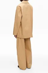 Chaqueta color tostado con diseño de rayas diplomáticas verticales en tono claro, solapas de muesca, cierre frontal de dos botones y bolsillos laterales con solapa.