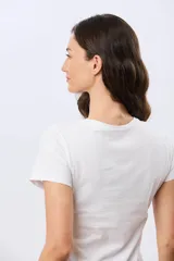 Remera beige de manga corta con cuello redondo, confeccionada en algodón con un diseño delantero que combina estampa floral y detalles bordados.