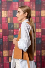 Chaleco color marrón de cuero sintético, con cuello en V, sin mangas, cierre frontal con un botón y dos bolsillos de parche.