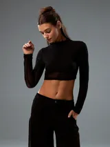 Top negro con cuello alto, mangas largas de tul y corte crop.