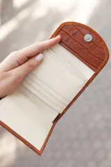 Billetera marrón de cuero con textura tipo cocodrilo en la parte inferior y solapa de gamuza en la parte superior.