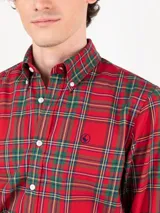 Camisa de hombre de corte regular fit, confeccionada en algodón con estampado de cuadros tartán en tonos rojo, verde y amarillo. Tiene cuello button down, cierre frontal con botones, mangas largas con puños simples y logo bordado en el pecho.