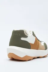 Zapatilla urbana de diseño contemporáneo con capellada que combina paneles de diferentes texturas en color negro, ajuste con cordones y suela robusta de color blanco.