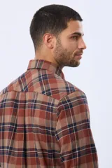 Camisa de viyela a cuadros en tonos marrón, azul marino y gris, con cuello clásico, cierre frontal con botones, mangas largas y un bolsillo en el pecho.