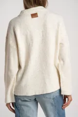 Sweater de punto con cuello polo y cierre frontal de tres botones. Presenta un diseño de corte oversize, mangas largas y textura acanalada.
