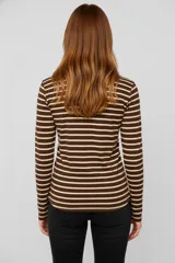 Remera de manga larga con cuello redondo y abertura frontal con botones. Presenta un patrón de rayas horizontales blancas y negras, y un pequeño bolsillo negro en el pecho.