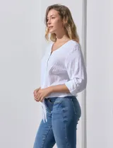Blusa blanca de algodón marca Dash, con escote en V, abertura con botones, mangas 3/4 regulables con presilla y ruedo anudado.
