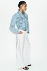 Cazadora corta de denim color celeste con cuello solapa, manga larga y hombreras. Cuenta con bolsillos delanteros con solapa y cierre frontal de botones metálicos.