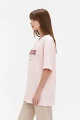 Remera de algodón negra con cuello redondo y mangas cortas, de corte holgado. Presenta estampado frontal en tonos de verde con la inscripción 'New York City Brooklyn' y el logo 'NY' rodeado de laureles.