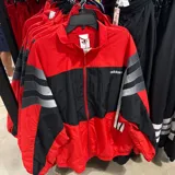 Campera deportiva Adidas con cierre frontal, diseño color block en rojo y negro, con las icónicas tres tiras en gris en las mangas.
