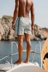 Short de baño con estampado ornamental de estilo paisley y rayas verticales en tonos azules, verdes y blancos. Cuenta con cintura elástica, dos bolsillos laterales y un bolsillo trasero.