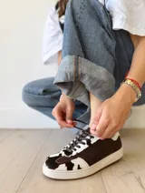 Zapatilla deportiva de cuero con estampado de vaca (pelo), color marrón y blanco. Suela blanca gruesa.