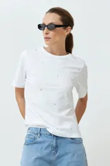 Remera blanca de algodón con cuello redondo y apliques circulares plateados.