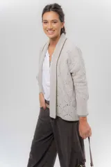 Saco tejido de lana color beige, con diseño abierto tipo kimono, detalles calados en las mangas y el cuerpo, y ribetes en contraste.