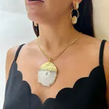 Collar con cadena de eslabones dorados y dije de piedra semipreciosa, posiblemente ágata, de forma semicircular. La parte superior del dije tiene un acabado metálico dorado martillado, mientras que la inferior es de piedra azul oscuro con vetas.