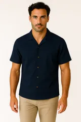 Camisa de lino color azul marino, de corte holgado, manga corta y cuello tipo solapa. Cuenta con cierre frontal de botones marrones.