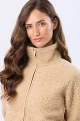 Campera de corderito color beige con cuello alto, cierre frontal y bolsillos laterales.