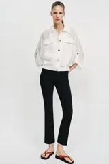 Blusa negra de cuello solapa y manga corta, con bolsillos con solapa en el pecho, bajo elástico y cierre frontal con botones.