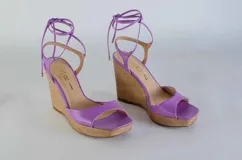 Sandalias de plataforma con taco corrido revestido en yute, confeccionadas en cuero color lila. Presentan diseño de puntera abierta y tiras largas para atar alrededor del tobillo.