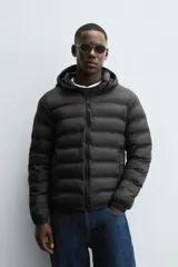 Campera puffer acolchada de corte regular fit en color negro, confeccionada en tejido técnico repelente al agua. Presenta cuello subido con capucha, cierre frontal de cremallera, mangas largas con puños elásticos y bolsillos laterales de vivo.
