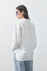 Camisa de manga larga de algodón en color blanco, con cuello clásico, cierre frontal de botones y silueta relajada.