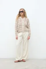 Campera de punto abierta con botones frontales, cuello redondo y mangas largas, con diseño geométrico en tonos crudo y beige.