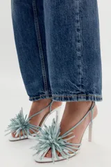 Sandalias de tacón alto y ancho, color blanco con tiras y detalle de flor decorativa en la parte delantera en tono celeste.
