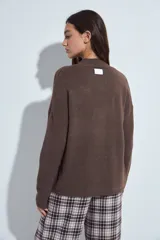 Sweater de punto gris con cuello a la base y diseño de trama geométrica en relieve. Presenta un calce relajado con mangas largas y puños tejidos.