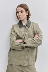 Campera de gabardina tostada, con cuello camisero de pana marrón, cierre frontal de botones metálicos y bolsillos delanteros aplicados con solapa.