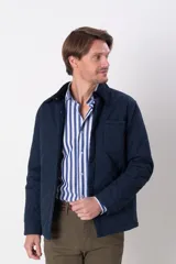 Campera azul marino capitoneada con cuello de pana, cierre frontal con botones a presión, bolsillos laterales y un bolsillo plaque en el pecho.