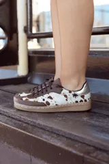 Championes de diseño artesanal con paneles de cuero vacuno con pelo estampado tipo animal print y detalles en cuero liso marrón. Presenta una pieza metalizada en el talón y suela de goma color caramelo.