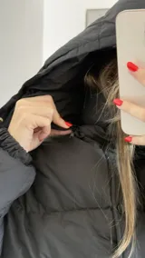 Campera puffer de corte holgado en color beige, con diseño acolchado, cuello alto y capucha desmontable. Cuenta con cierre frontal y botones a presión, además de puños elásticos.