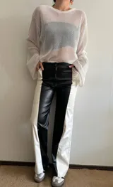 Pantalón largo de cuero sintético, corte recto, con diseño color block en blanco y negro.