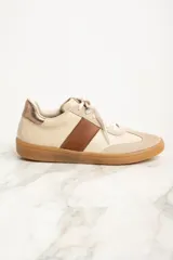 Zapatillas bajas color crema con puntera de gamuza beige, detalle de franja lateral en cuero marrón y contrafuerte en cuero metalizado color cobre.